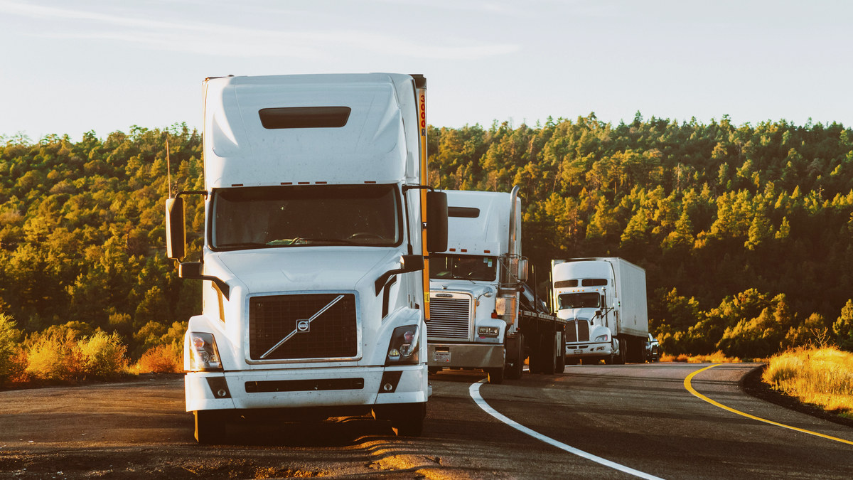 Line of semi trucks at golden hour illustrating how spot rates fall below contract 2026 while record diesel squeezes carrier margins