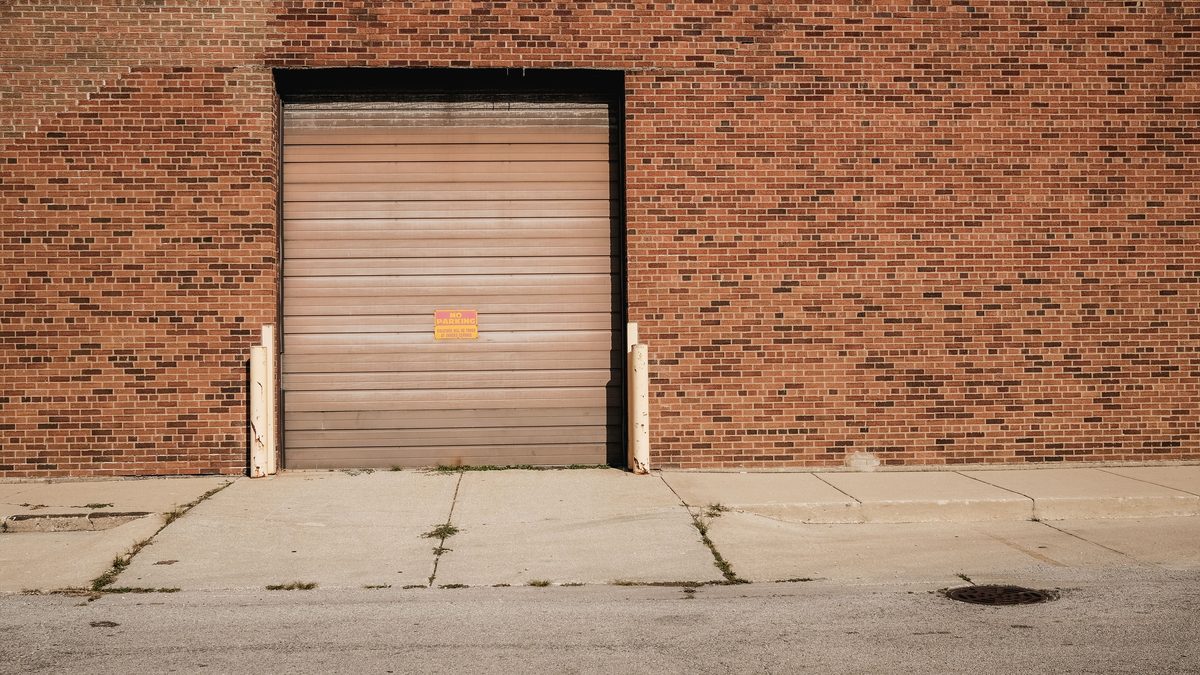 Closed loading dock door on a brick warehouse — trucking capacity crisis 2026